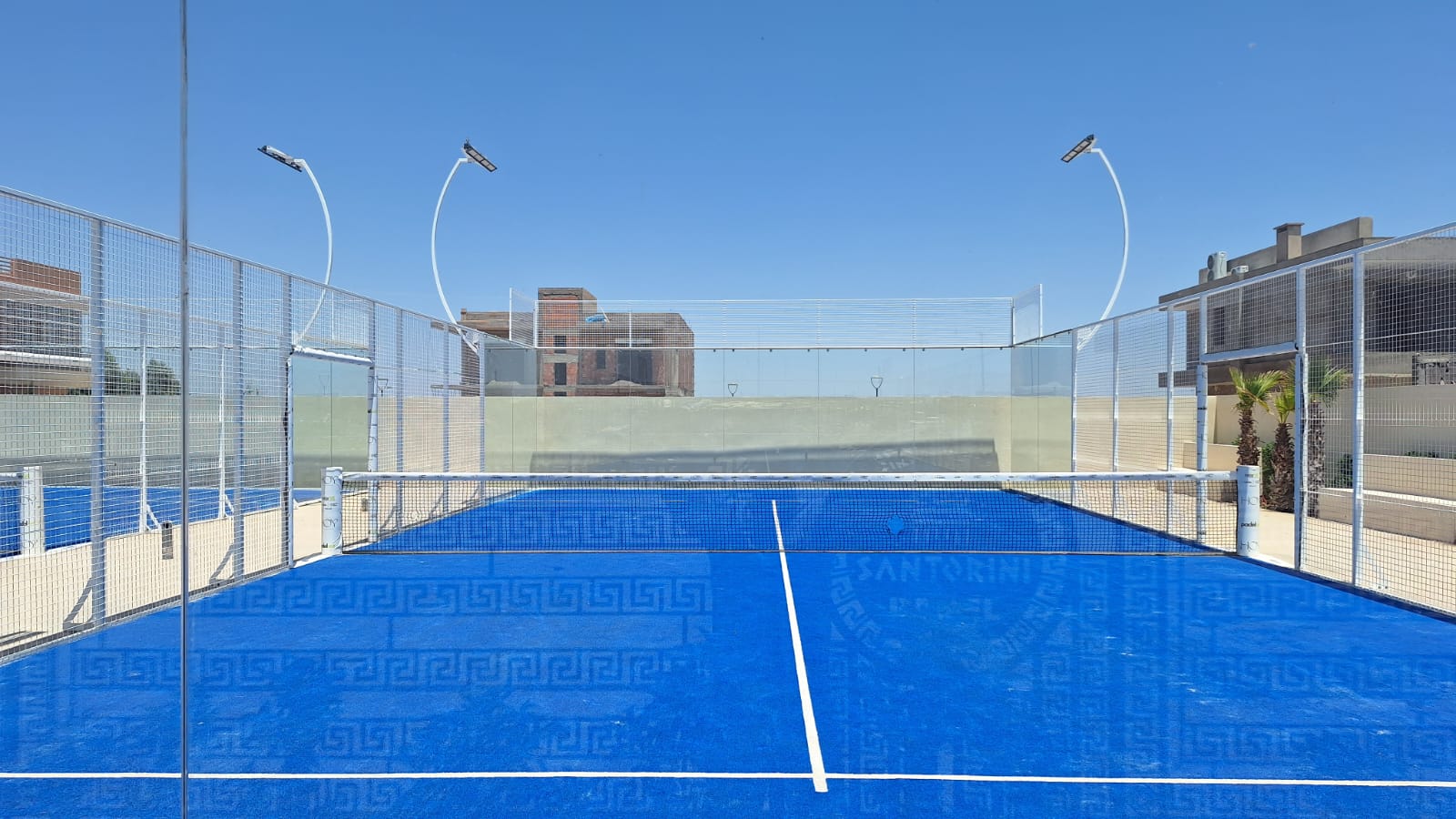 Vue frontale du terrain de padel Santorini, filet et parois vitrées